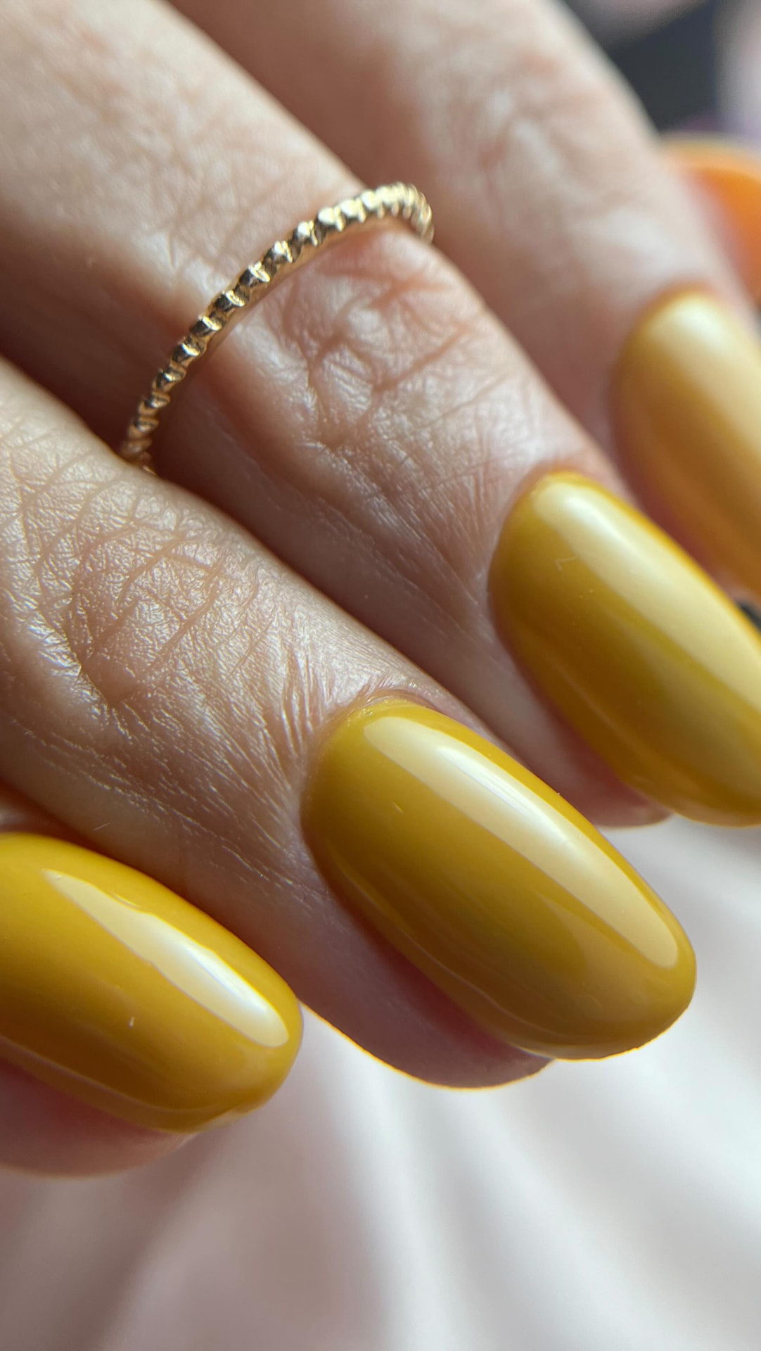 Manicura en color mostaza brillante con acabado espejo y anillo dorado